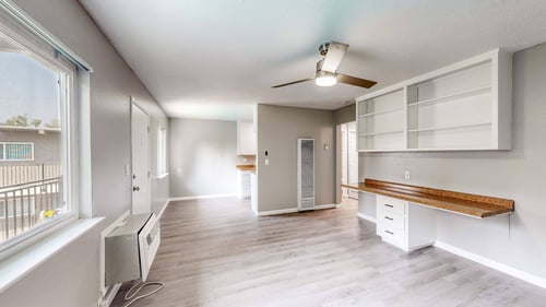 A well-lit, spacious room with a window, a bench, and a ceiling fan at Pennsylvania Place, Davis, CA