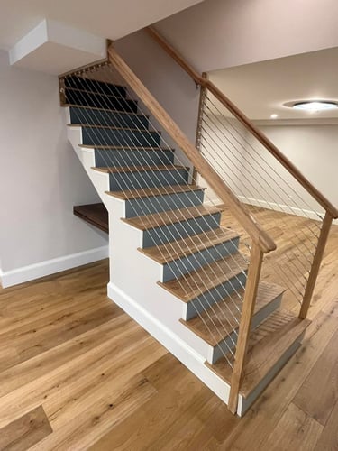 Modern residential staircase with wood railings, cable railing system, painted walls, and hardwood flooring.