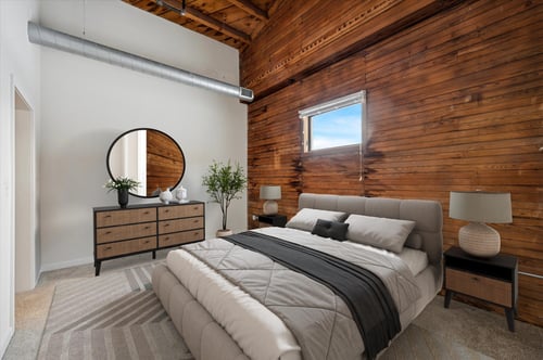 Bedroom with wood accent wall and neutral bedding at Oxford Mills Apartments, Philadelphia, PA