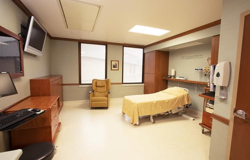 a labor and delivery room showing a birthing bed, recliner, storage cabinets and TV.