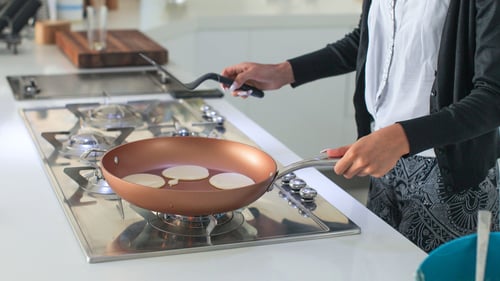 A woman cooks on a propane stove top.