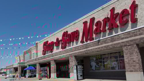 Woman and girl walking with shopping cart under bunting hanging from entrance of Shop-n-Save Market at Southfield Plaza - Bridgeview shopping center