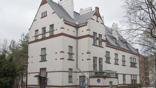 Valkotiilinen rakennus ulkoa kuvattuna.