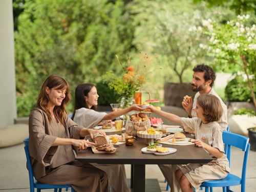 Eine Familie genießt ein entspanntes Frühstück im Freien. Frisch gebackenes Brot, Croissants und Brötchen stehen auf dem Tisch. Morgengold bringt regionale Backwaren frühmorgens an die Haustür – bequem, zuverlässig und mit höchster Qualität.