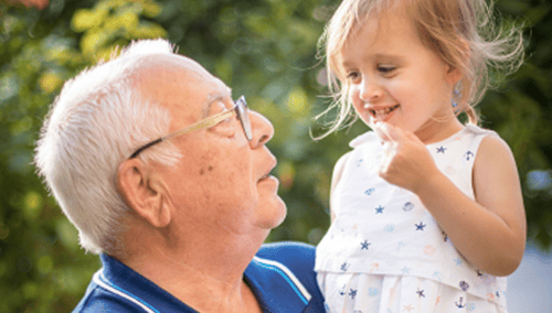 A grandfather carrying his granddaughter.