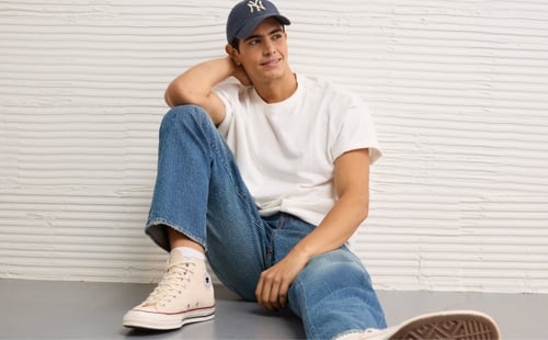 man sitting in jeans and converse with hat on