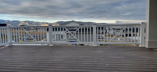 A balcony view featuring white vinyl railings with a decorative cross-hatch pattern on a dark composite deck in Idaho Falls, Idaho.