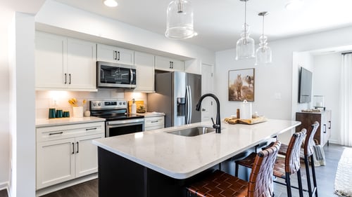 Gourmet kitchen and island with white cabinets in a townhome built by DRB Homes Pintail Landing community.