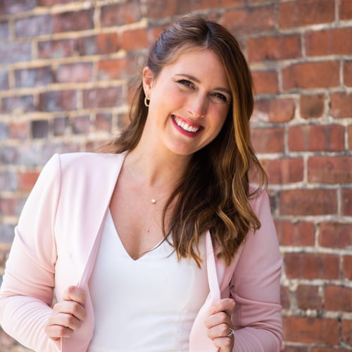 Agent Lauren Yohman standing and smiling wearing white top and pink blazer
