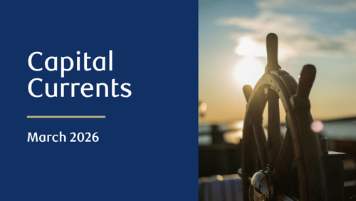Close-up of a wooden ship steering wheel, with the sun setting over water in the background.