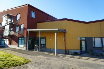 Kuvassa on toimintakeskus Nyyttipuisto ulkoa. Uuden näköinen rakennus on toisesta osasta kolmikerroksinen ja ruskea, toisesta osasta matalampi ja keltainen.