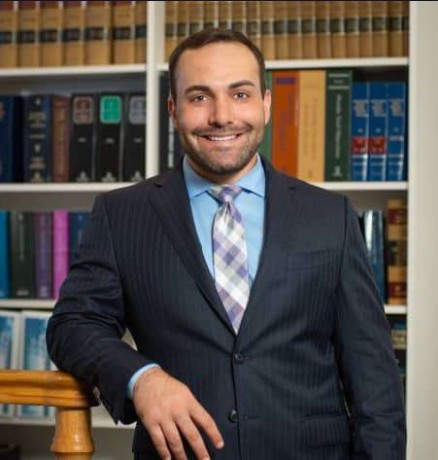 Adam Shapiro personal injury lawyer standing in front of a bookcase.