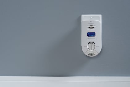 Kidde CO + IAQ device plugged in on a gray wall.