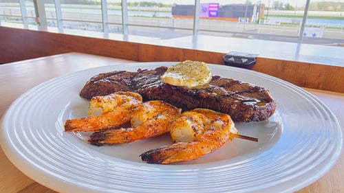 Sulky's Restaurant and Bar. Steak and shrimp plated on a table with a view of the race track.