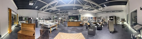 Panoramablick in den modernen Showroom von Preuss Raumgestaltung Paderborn mit JOKA-Bodenproben, JAB Anstoetz-Stoffen, Rasch- & Schöner Wohnen-Tapeten, Forbo Marmoleum, Unland-Gardinen, Indes Fuggerhaus-Textilien, großer Auswahl an Mustern, Theke und inspirierender Industrie-Atmosphäre unter hoher Decke