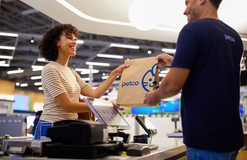 Petco cashier handing a customer her bag at checkout