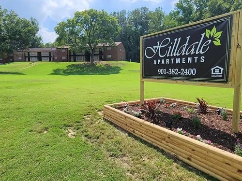 A sign for Hilldale Apartments with a phone number on it