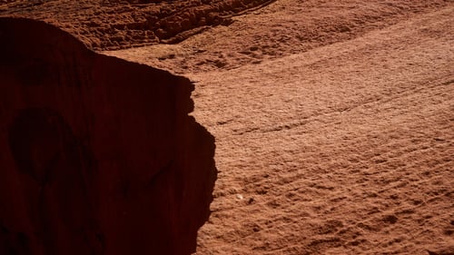 Close-up of rugged red desert rock terrain with deep shadows and textured surface.
