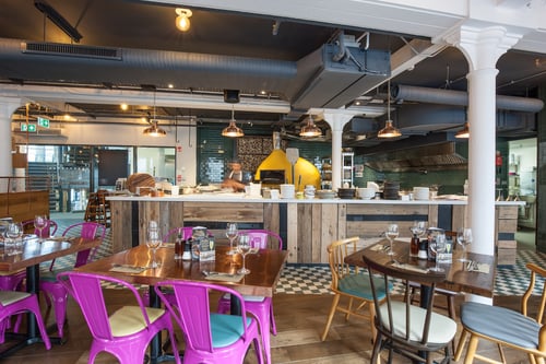 Interior of Zizzi Belfast Victoria Square showing wooden tables, pendant lighting, and modern comfortable seating.