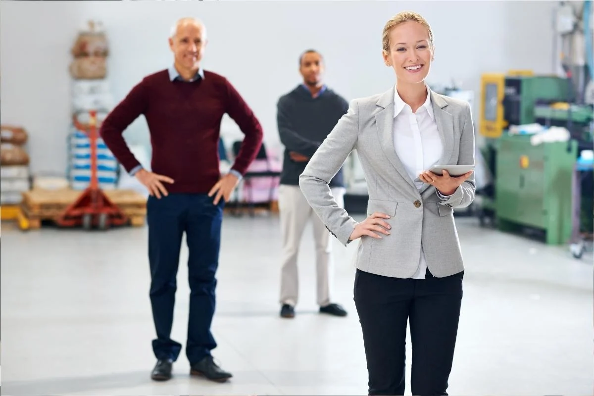 Three professionals standing together on a factory or warehouse floor