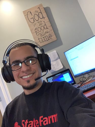 Team member sitting at desk and smiling in gray and red State Farm hoodie