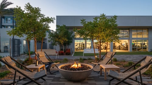 Outdoor firepit at Ariva Luxury Residences with surrounding chairs and stone patio.