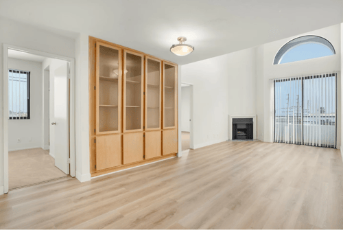 Living area with wood inspired flooring, built in cabinetry and large windows at Midvale Court Apartments in Westwood, LA 90024