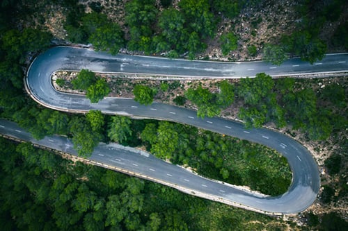 Aerial view of a winding road surrounded by trees.