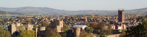 Wide-angle view of Ludlow, England, featuring the prominent "Cathedral of the Marches" church tower against a clear sky.