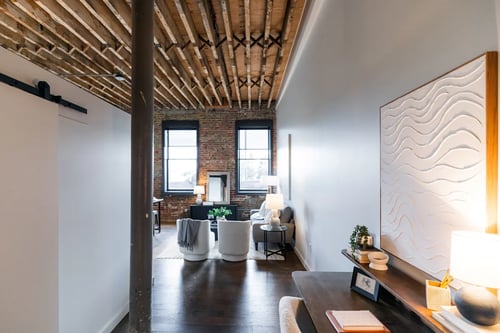 A living room with a white couch and a wooden floor at Plant 1 Lofts, N. Newton Iowa
