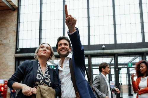 Couple at the airport, pointing to a sign up ahead.