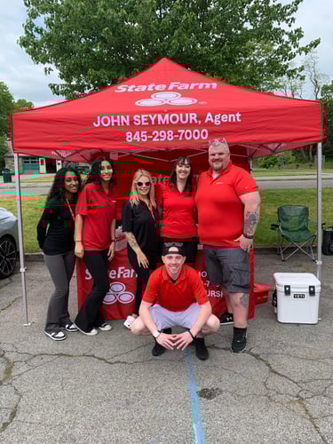 Agent John and five team members standing and smiling by red State Farm tent at Lake Effect Car Meet