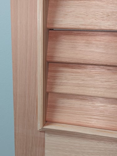 Close-up of custom louvered shutter showing wood grain and louvers