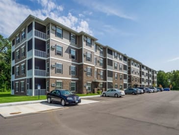 an apartment building with cars parked in a parking lot at Arbor Ridge, Forest Lake