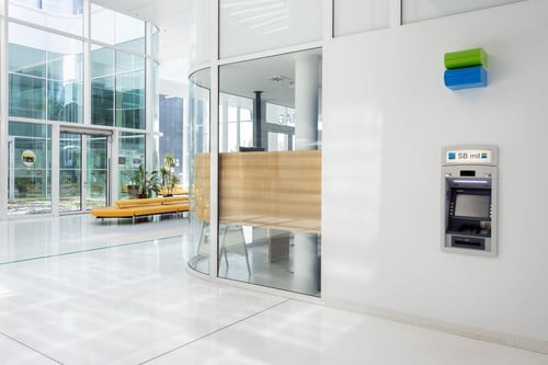 Schrägansicht des Bankomaten aus mittlerer Entfernung, die den gesamten Automaten und den umgebenden Bereich umfasst.