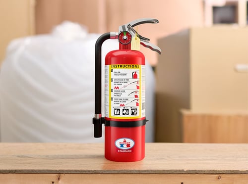 A Badger standard fire extinguisher sits on a table.