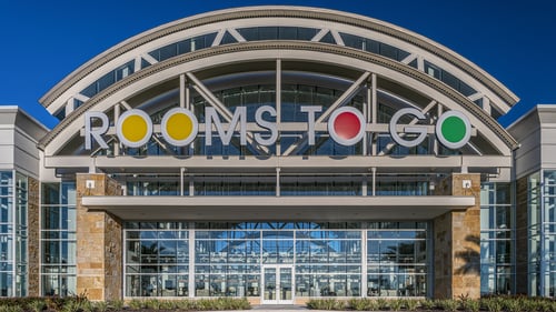 Rooms To Go showroom entrance featuring contemporary design under clear blue sky