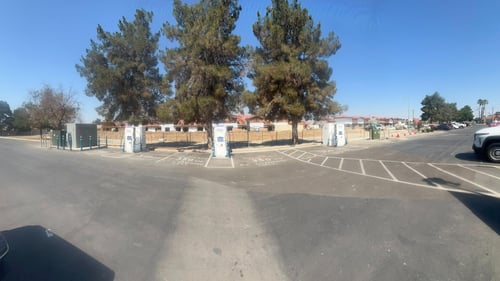 Several EVgo fast charging units installed in marked parking spaces at a public charging station, with EVgo logos on the chargers, protective bollards around each unit