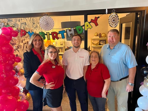 Agent and Team posing in front of balloons and office