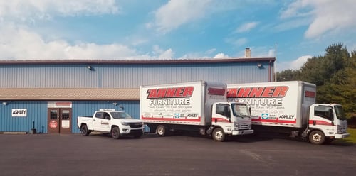 Branded R.A. Ahner Furniture & Appliances delivery truck parked in front of the store on a clear day.