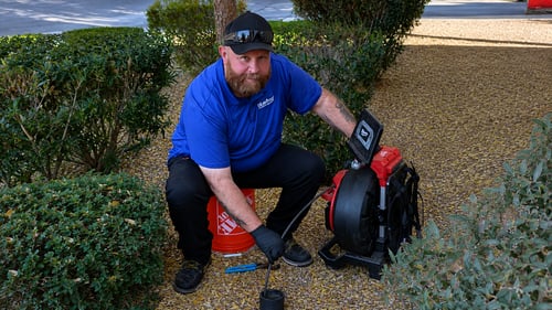Plumber using a sewer camera to inspect a residential sewer bluefrog plumber performing a sewer line video inspection with camera equipment