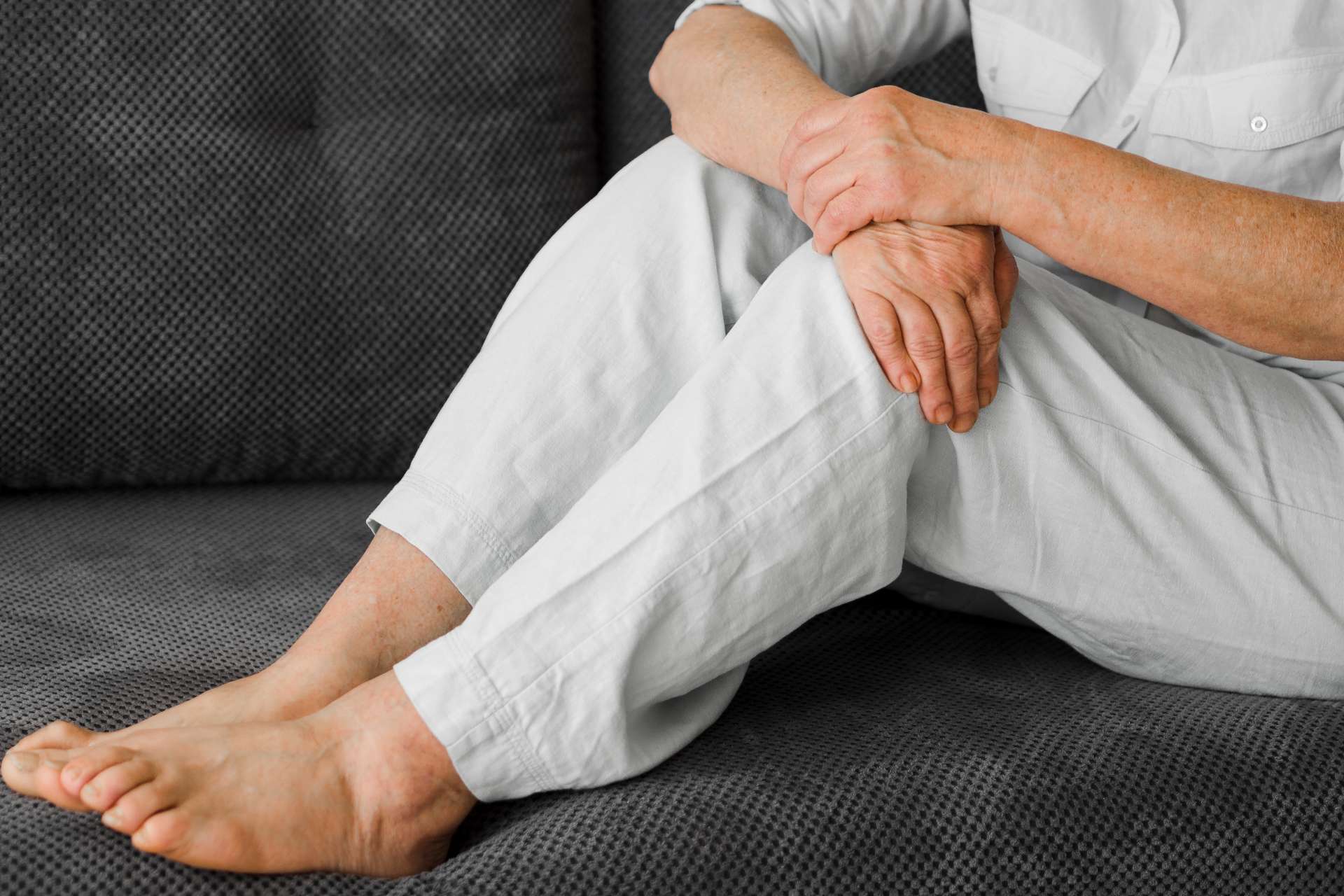 elderly person holding their knee and barefoot