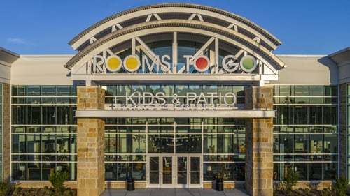 Exterior of the Rooms To Go store in Clearwater, Florida, at night, featuring illuminated signage and large glass windows showcasing the Kids & Patio sections