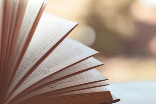Close-up shot of a book on a desk with its pages being flipped.