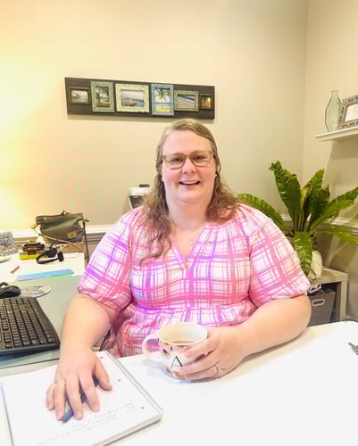 team member sitting at a desk in a pink shirt