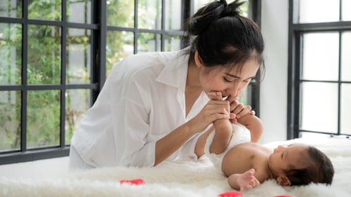 A mom plays and kisses her baby's feet.