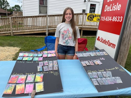 Child standing with bracelets outside of agency