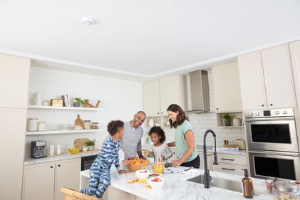 Family in the kitchen cooking with a Kidde Combination alarm overhead to help detect Smoke or Carbon Monoxide incidents.