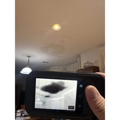 Restoration technician using an infrared camera to see the boundaries of the water damage