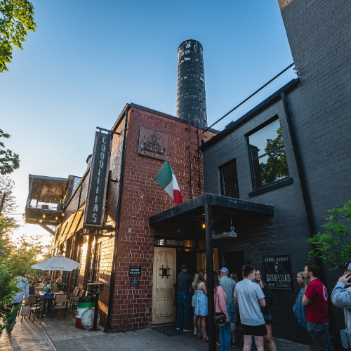 Exterior of Goodfellas Pizzeria Distillery District with Italian flag and brick building.